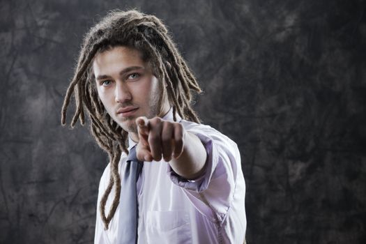 Young business man in suite, pointing at camera