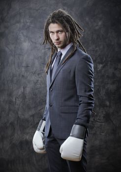 Portrait of a young business man wearing boxing gloves against grunge background