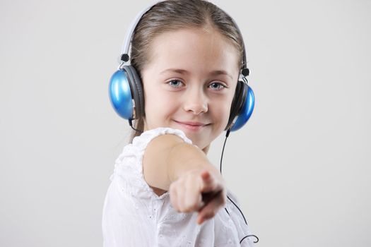 little pretty child  pointing at viewer, she listening music in headphones
