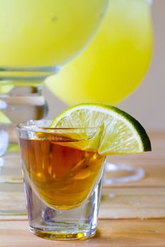 Margaritas at a Mexican restaurant with a shot of tequila and a lime.