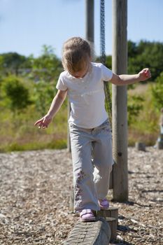 young girl on wooden balance beam at playground