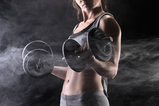 Young woman lifting the dumbbells