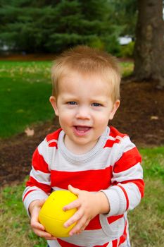 A portrait of a young boy playing outdoors wearing a red and white striped shirt.