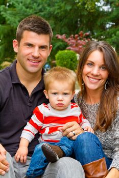 A husband and wife have their first child and pose for a portrait with the boy.