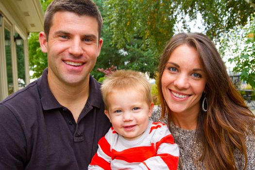 A husband and wife have their first child and pose for a portrait with the boy.