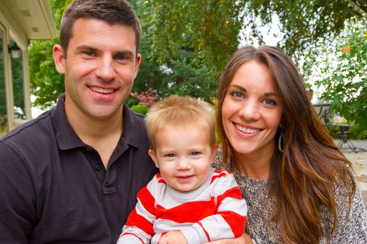 A husband and wife have their first child and pose for a portrait with the boy.