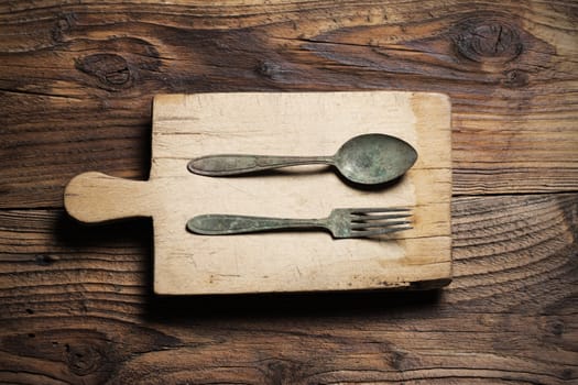 Spoon and fork, on old wood background