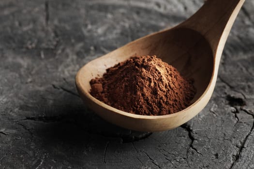 Wooden spoon full of cocoa powder, close up