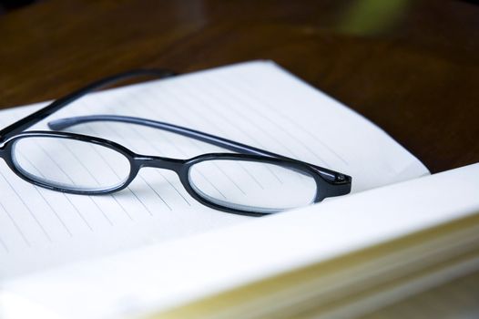 close up eyeglasses put on open notebook