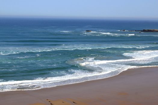 a sandy beach beside the sea under a blue sky