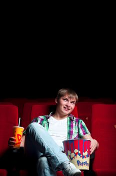 man in a movie theater, watching a movie and drink a drink