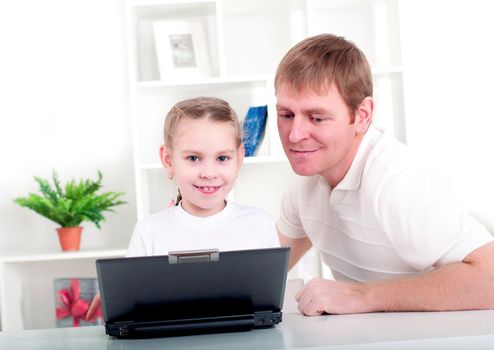 Father and daughter are working together for a laptop at home