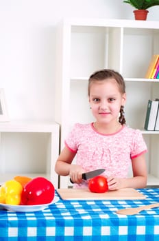 beautiful young girl cooking vegetables for a salad, working in kitchen