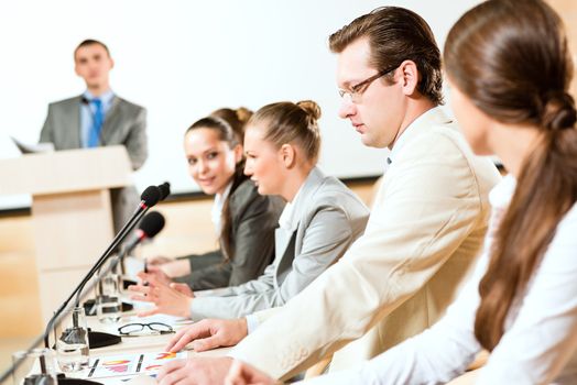 businessmen communicate at the conference, sitting at the table, on the table microphones and documents