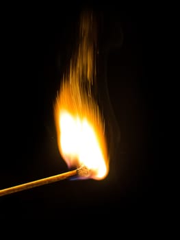 Burning match over black background