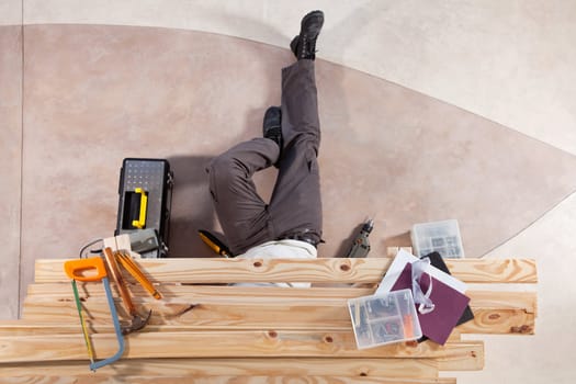 Man repairing under the wooden plank with tools