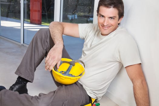 Portrait of young man sitting with construction helmet
