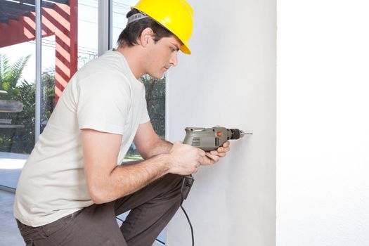 Young man with electronic drill machine working