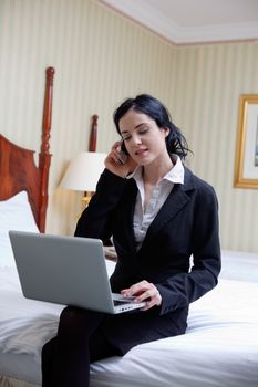 Business woman talking on cell phone while working on laptop