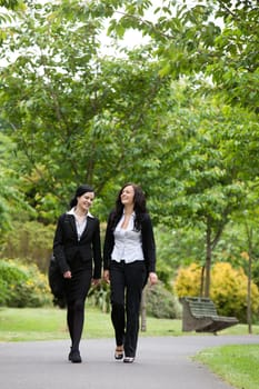 Full length of two female executives walking in park