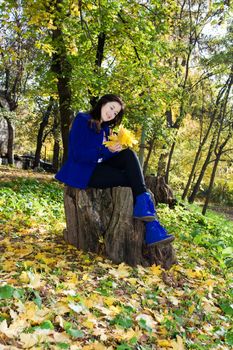 attractive young caucasian woman in warm colorful clothing lying down on yellow leaves outdoors smiling