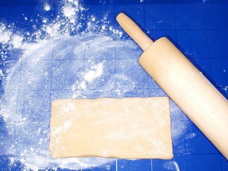 Dough on blue silicon mat, with wooden pin