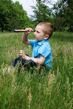 little boy sits on the green grass and playing with a toy