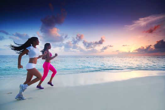 Fitness sport women running on beach at sunset