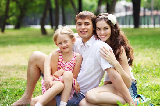 Young Family Outdoors on the grass in Park in summer