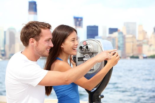 Tourists couple travel in New York. Beautiful young interracial young couple on travel looking at Manhattan and New York City skyline from Ellis Island. Asian woman, Caucasian man.