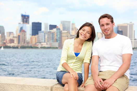 Young couple dating in New York. Portrait of multi-ethnic couple with Manhattan and New York City Skyline in background. Asian woman, Caucasian man tourists on Ellis Island, New York City, USA