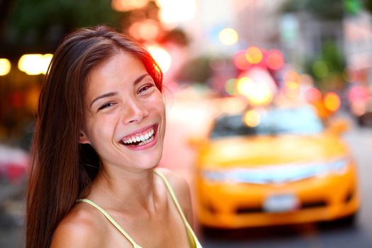 Happy New York City girl. Woman smiling laughing joyful on Manhattan with yellow taxi cab in background. Fresh energetic mixed race Caucasian / Chinese Asian female model smiling candid and real.