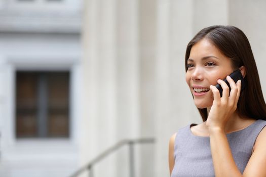 Woman businesswoman lawyer talking on smart-phone outdoors in front of courthouse. Beautiful young mixed race Caucasian / Asian Chinese professional woman.