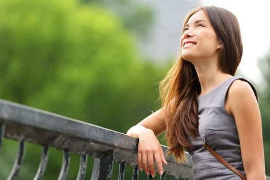 Business woman thinking in Central Park, New York City. Young female professional businesswoman thinking smiling happy outdoors. Mixed race Caucasian / Asian Chinese woman in her 20s.