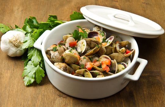 a delicious clams soup with tomatoes on wooden table