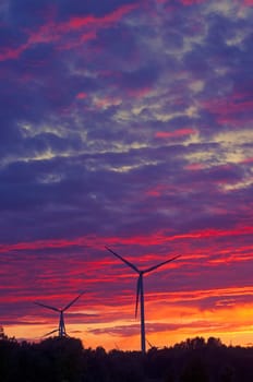 A silhouette of windturbines on a amazing sunset