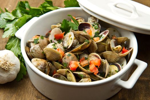 a delicious clams soup with tomatoes on wooden table