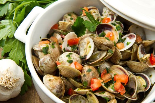 a delicious clams soup with tomatoes on wooden table