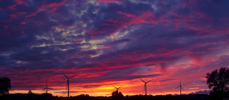 A silhouette of windturbines on a amazing sunset