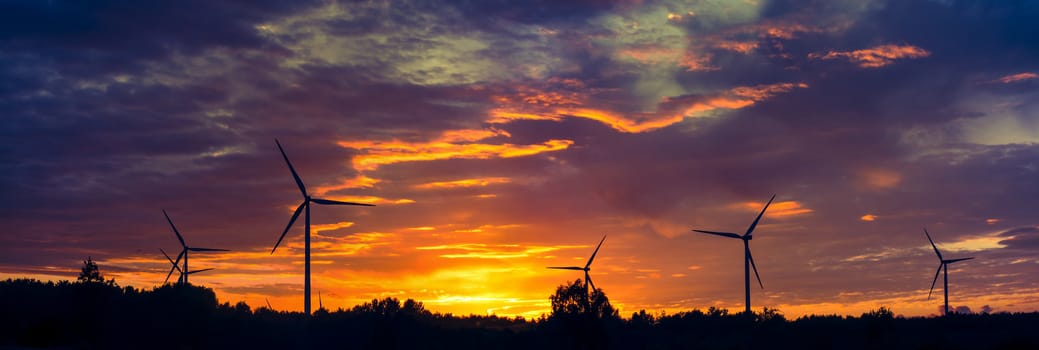 A silhouette of windturbines on a amazing sunset
