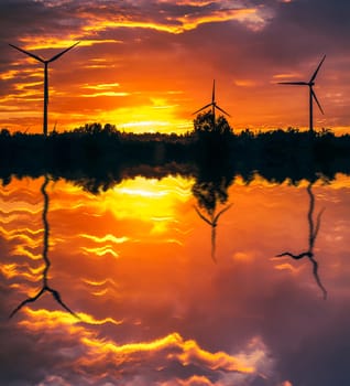 A silhouette of windturbines on a amazing sunset