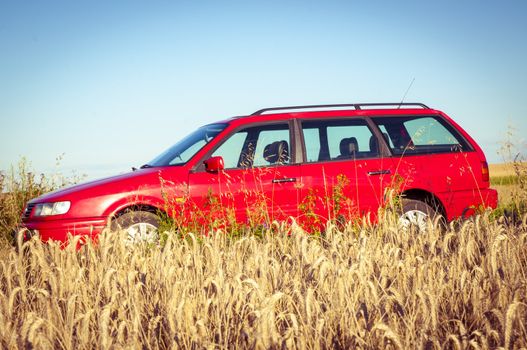 Red car parked near the wheat field