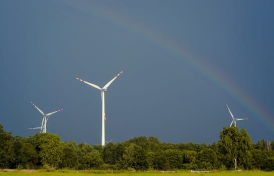 Windturbines against blue sky and rainbow