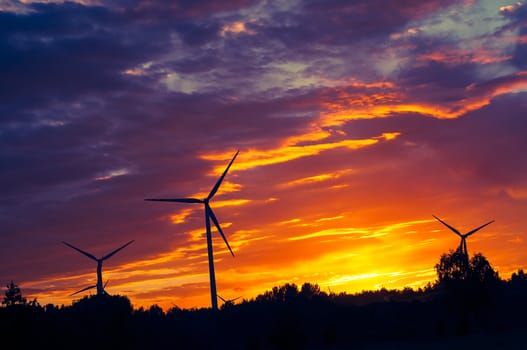 A silhouette of windturbines on a amazing sunset