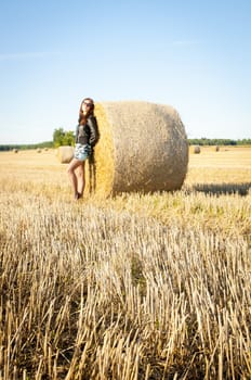 An image of brunette girl portrait and straw bale 