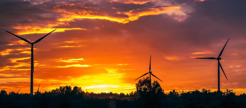 A silhouette of windturbines on a amazing sunset