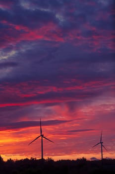 A silhouette of windturbines on a amazing sunset