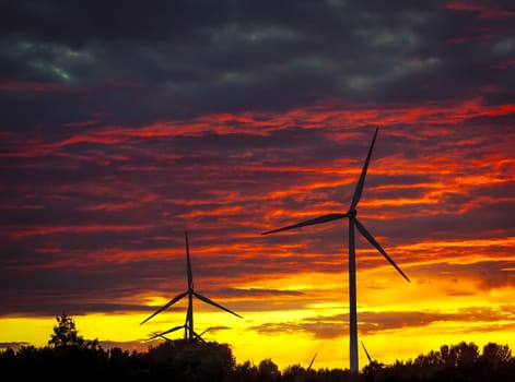 A silhouette of windturbines on a amazing sunset
