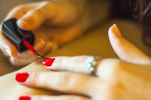 Girl paints her nail into red color. Shallow DOF