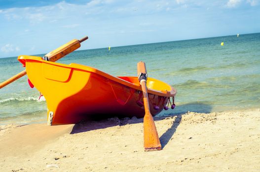 An image of orange rescue boat on the beach of baltic sea